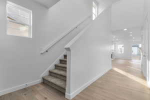 Staircase with healthy amount of natural light, wood-type flooring, and a high ceiling