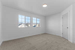 Empty room featuring baseboards and light colored carpet