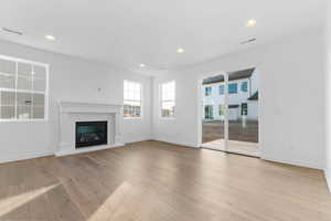 Unfurnished living room featuring a glass covered fireplace, recessed lighting, and light wood-type flooring