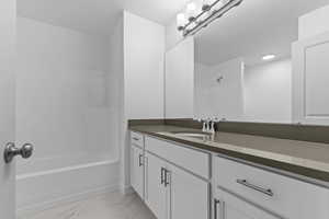 Bathroom featuring vanity, shower / washtub combination, and light marble finish floors