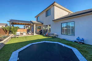 Back of property featuring a patio area, stucco siding, a fenced backyard, and an outdoor hangout area