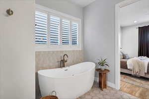 Full bathroom with a freestanding tub, light tile patterned floors, connected bathroom, and tile walls