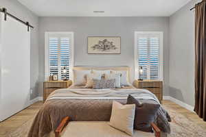Bedroom featuring a barn door and wood finished floors