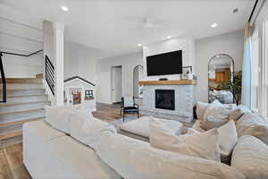 Living area featuring a ceiling fan, stairs, arched walkways, wood finished floors, and recessed lighting