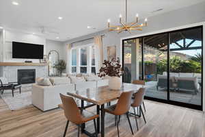 Dining space with recessed lighting, light wood-style floors, a fireplace, a ceiling fan, and a chandelier