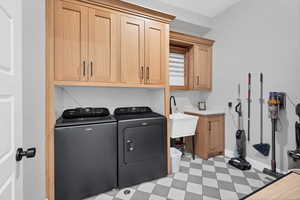 Laundry area featuring light flooring, cabinet space, and washer and clothes dryer