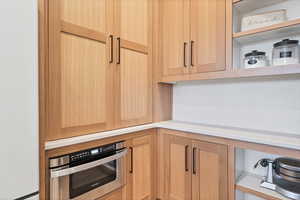 Kitchen with light brown cabinets, open shelves, freestanding refrigerator, light countertops, and stainless steel oven