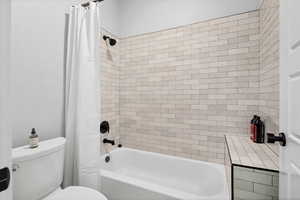 Bathroom with shower / bath combo with shower curtain and toilet