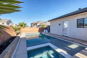 View of swimming pool featuring a fenced backyard, a patio area, and a pool with connected hot tub