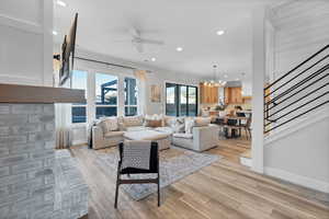 Living area featuring stairs, recessed lighting, light wood-style flooring, a chandelier, and a ceiling fan