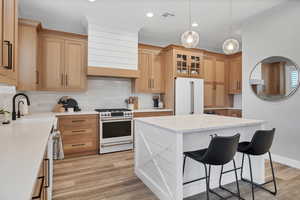 Kitchen featuring tasteful backsplash, white appliances, a breakfast bar area, decorative light fixtures, and recessed lighting