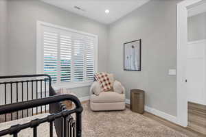 Bedroom with wood finished floors, a crib, and recessed lighting