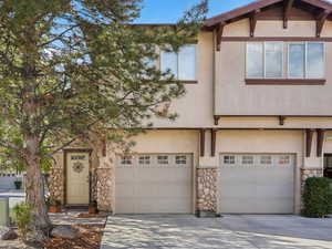 View of front facade with stone siding, stucco siding, and a garage