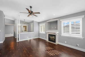 Living room with plenty of natural light, dark wood-style flooring, a ceiling fan, a fireplace with flush hearth, and recessed lighting