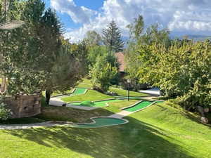 View of community featuring a yard, view of wooded area, and an area to practice putting