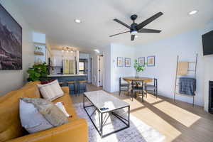 Living room with light LVP flooring, ceiling fan, a textured ceiling, and a fireplace