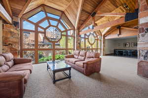 Carpeted living room with high vaulted ceiling and a wooden ceiling with exposed beams