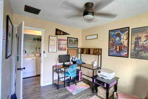 Home office with wood finished floors, washing machine and clothes dryer, a textured ceiling, and a ceiling fan