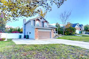 View of front of home with concrete driveway, a chimney, and an attached garage