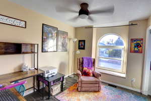 Sitting room with ceiling fan, a textured ceiling, and wood finished floors