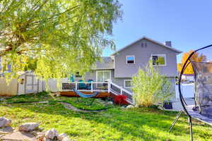 Rear view of house with a trampoline, a deck, a storage unit, and a chimney