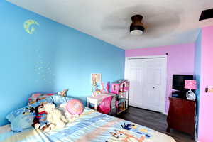 Bedroom featuring a ceiling fan, dark wood-style floors, a closet, and a textured ceiling
