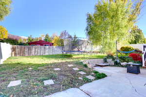 Fenced backyard with a trampoline and a patio area