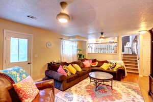 Living room with a textured ceiling, wood finished floors, and stairs