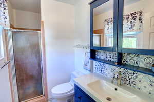 Full bath with vanity, a stall shower, and backsplash