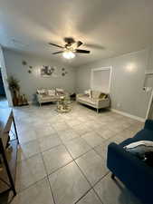 Living area featuring a textured ceiling, light tile patterned flooring, and a ceiling fan