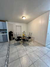 Dining room with light tile patterned floors and a textured ceiling