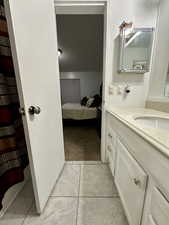 Bathroom with vanity, ensuite bathroom, a shower with curtain, light tile patterned floors, and light carpet