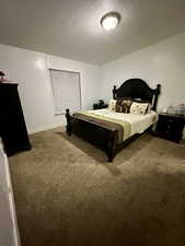 Carpeted bedroom featuring a textured ceiling and baseboards