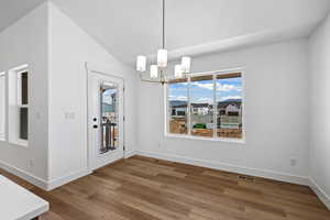 Unfurnished dining area with a chandelier, dark wood-type flooring, vaulted ceiling, and a textured ceiling