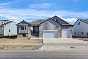 View of front facade with board and batten siding, stone siding, concrete driveway, and an attached garage