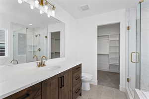 Full bathroom with a walk in closet, vanity, light tile patterned floors, and a shower stall