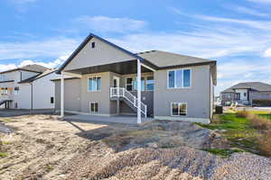 Rear view of house featuring a patio, stucco siding, a shingled roof, and stairs
