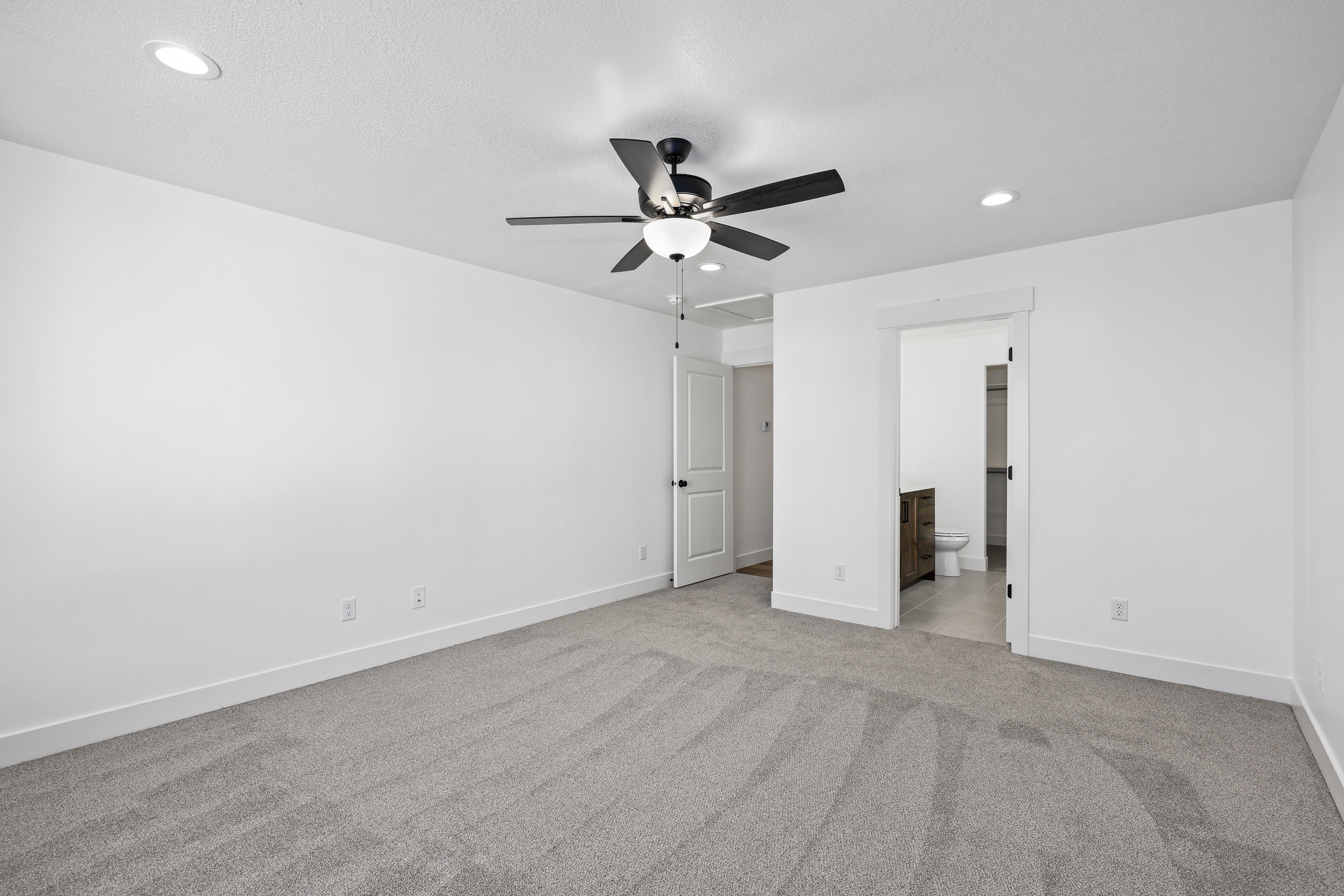 Unfurnished bedroom featuring light colored carpet, recessed lighting, a ceiling fan, and ensuite bathroom