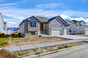 View of front of house featuring concrete driveway, a mountain view, stone siding, board and batten siding, and a garage