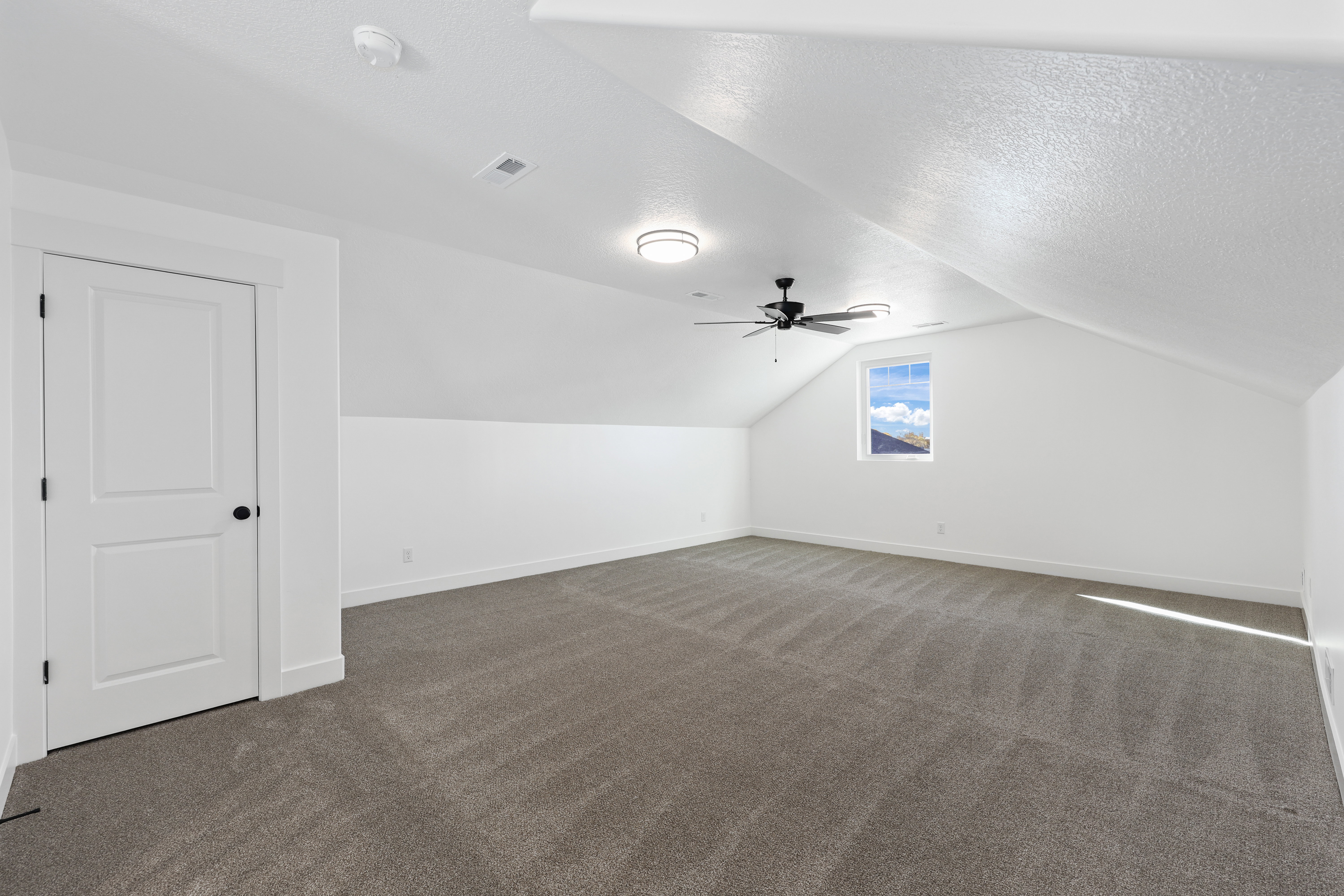 Additional living space with vaulted ceiling, dark carpet, a textured ceiling, and a ceiling fan