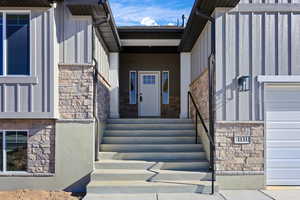 Doorway to property featuring stone siding, board and batten siding, and a garage