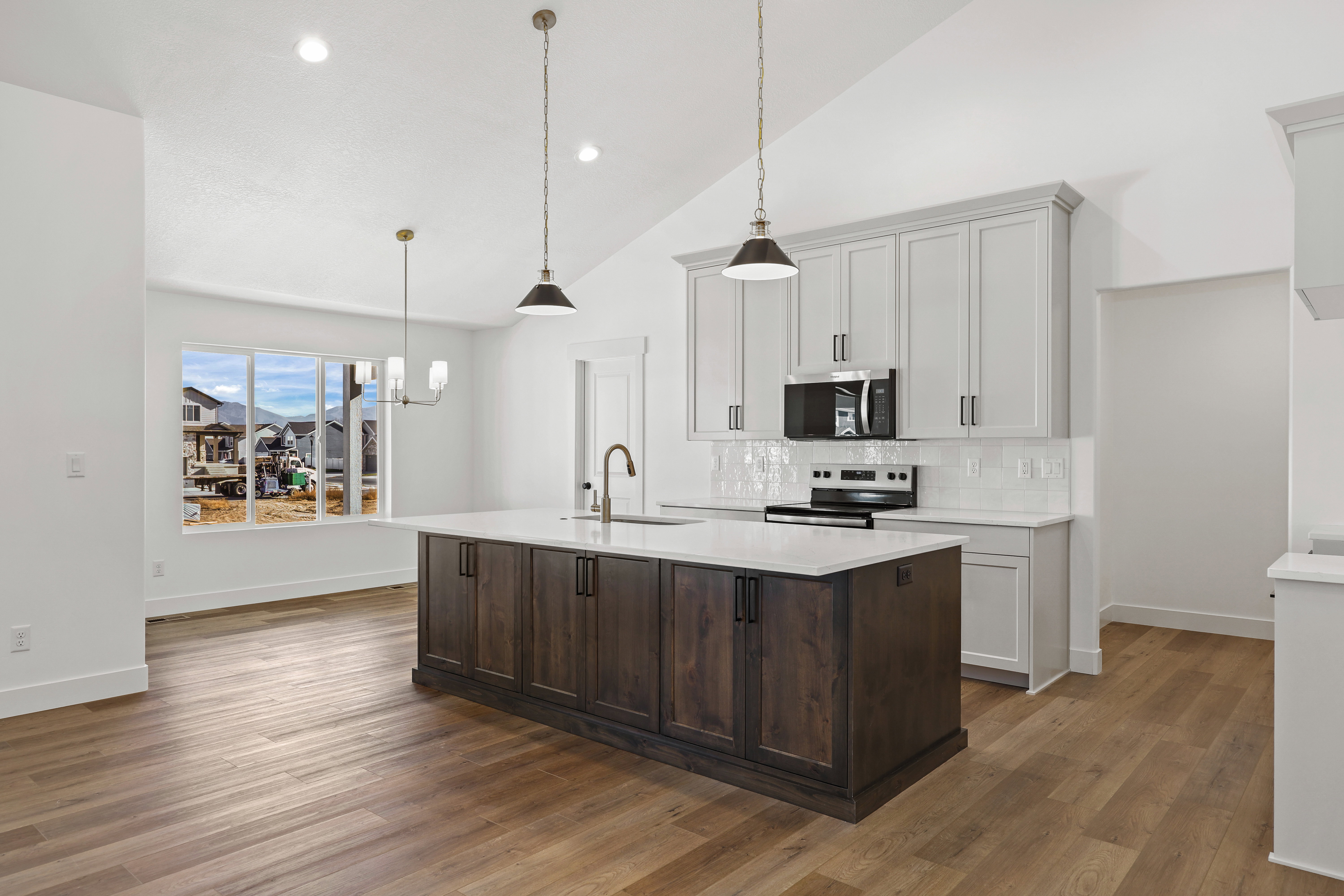 Kitchen with a kitchen island with sink, stainless steel appliances, hanging light fixtures, dark brown cabinetry, and tasteful backsplash