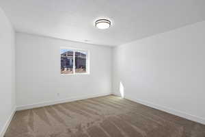 Carpeted empty room with a textured ceiling and baseboards
