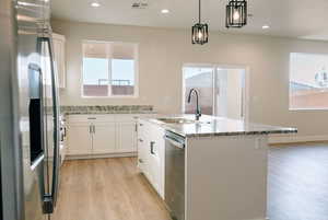 Kitchen featuring stainless steel appliances, white cabinets, light stone counters, light wood-type flooring, and recessed lighting