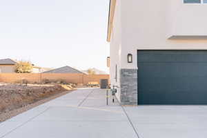 View of side of home featuring stucco siding, a fenced backyard, and stone siding