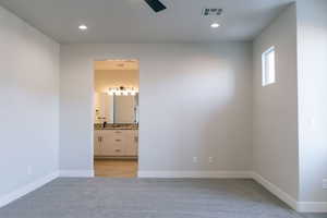 Unfurnished bedroom featuring light colored carpet, recessed lighting, a ceiling fan, and connected bathroom