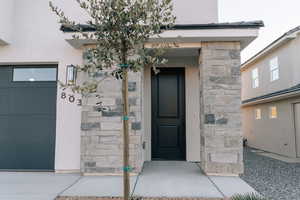 Doorway to property featuring stucco siding and stone siding
