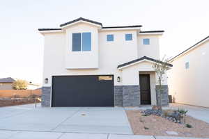 Contemporary house featuring stone siding, concrete driveway, a garage, and stucco siding