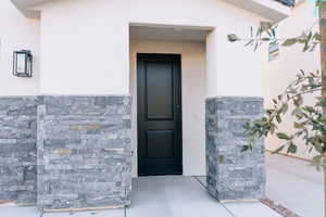 Entrance to property with stone siding and stucco siding