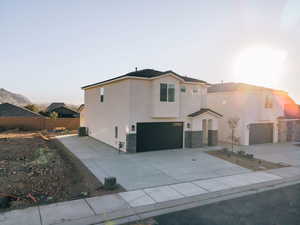 View of front of house with an attached garage, concrete driveway, stucco siding, and stone siding